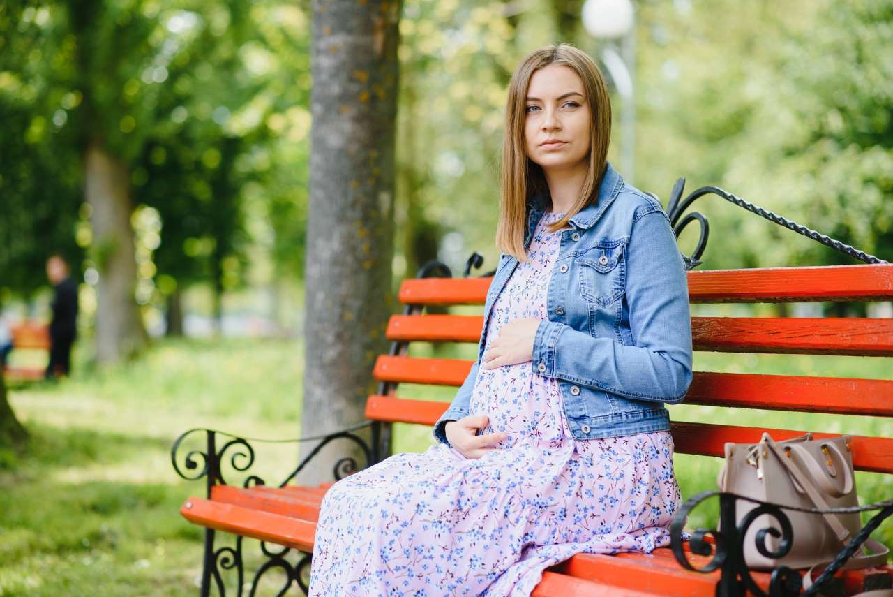 beautiful pregnant woman sitting on a park bench